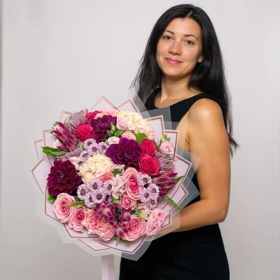 Hand-tied bouquet of purple and pink flowers wrapped in paper