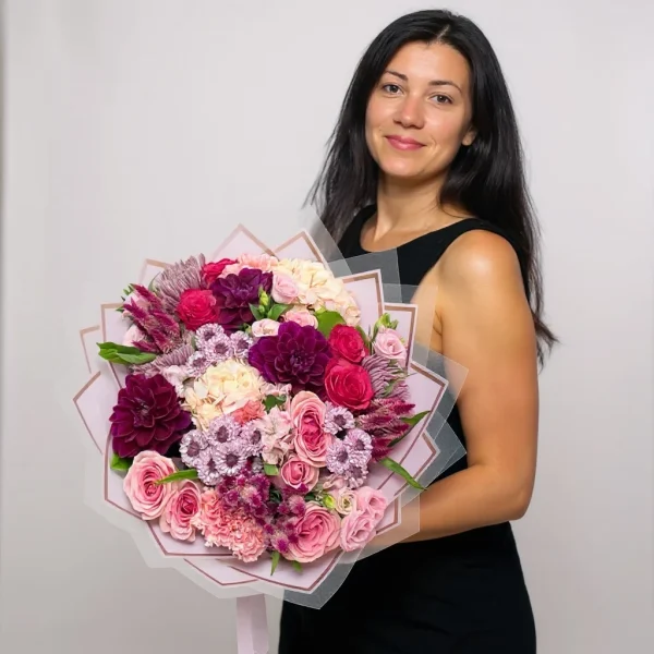 Hand-tied bouquet of purple and pink flowers wrapped in paper