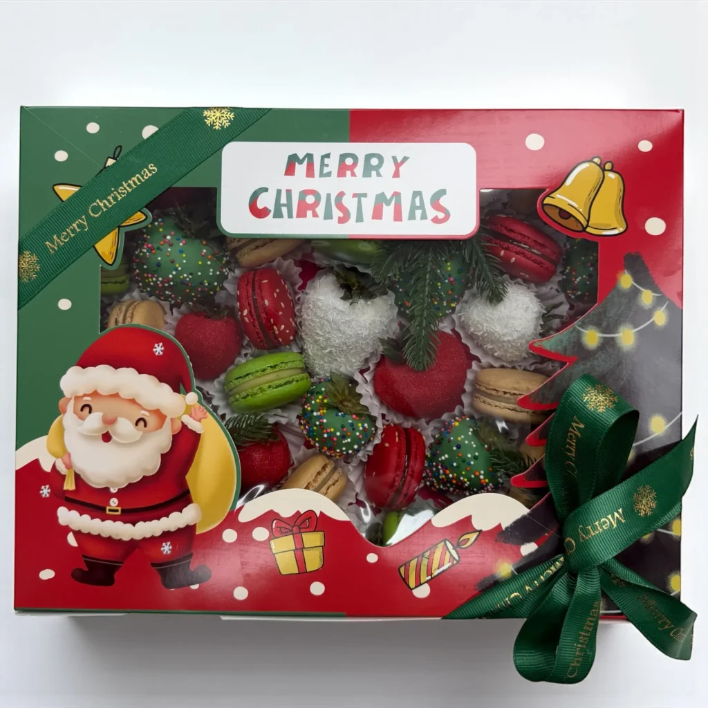 Christmas macaron and chocolate strawberry gift box open on decorated holiday table