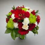 Bright red and green vase bouquet prepared for Christmas flower delivery